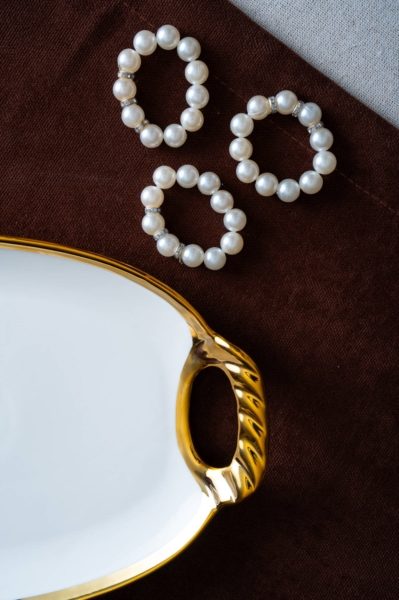 Lähikuva suorakaiteen muotoisesta valkoisesta posliiniastiasta, jossa on kultainen reuna ja koristeellinen kahva.