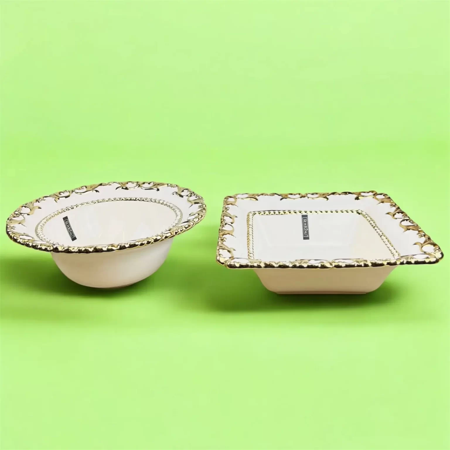 Två dekorativa keramiska serveringsskålar med guldmönster, belägna på en ljusgrön bakgrund.